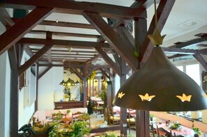 A restaurant with wooden beams and hanging pendant lights. - Pension Dessauer Hof (Halle (Saale))