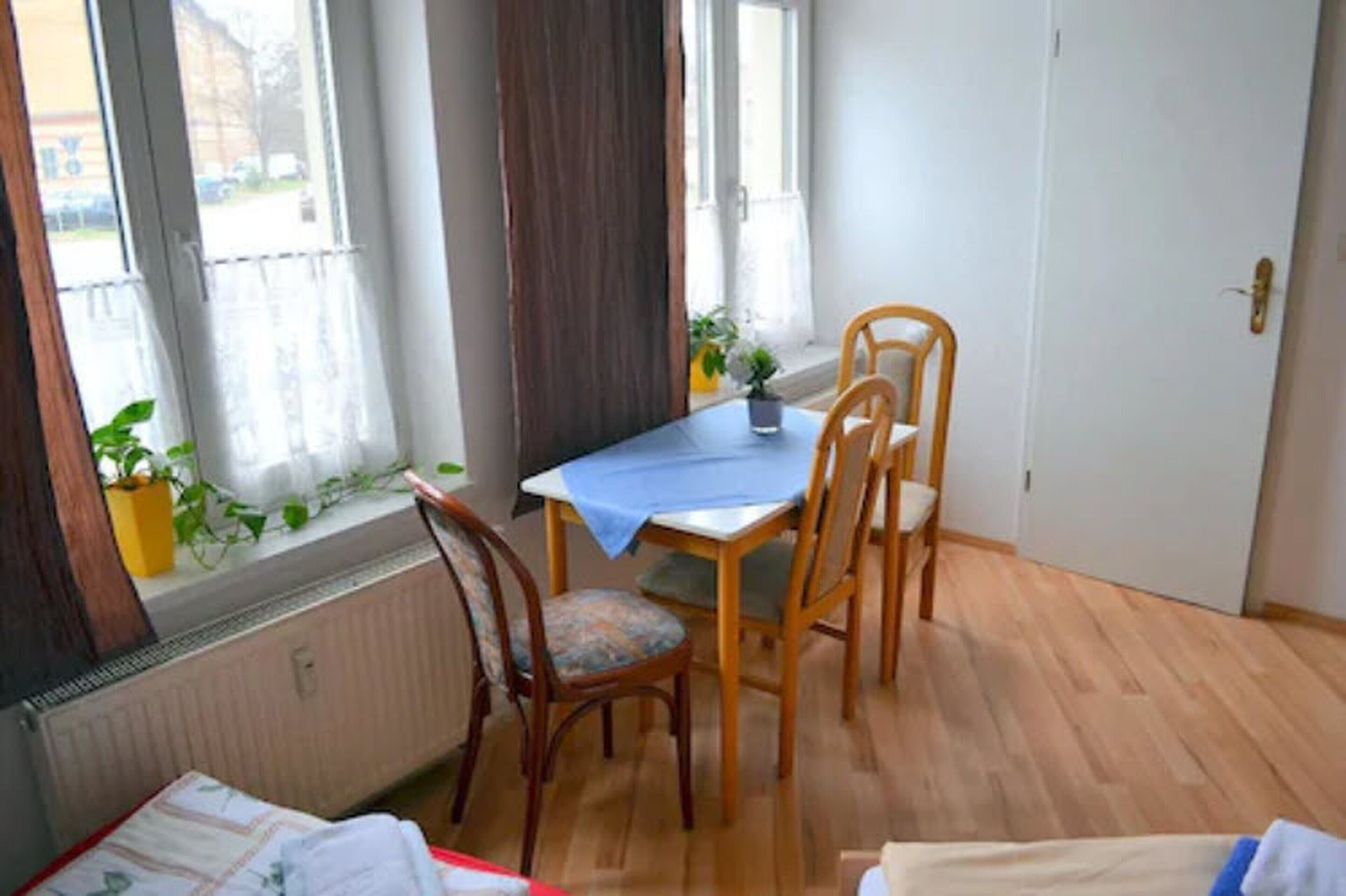 Ein kleiner Essbereich mit Tisch und vier Stühlen, einem Fenster mit Vorhängen und einer Heizung.