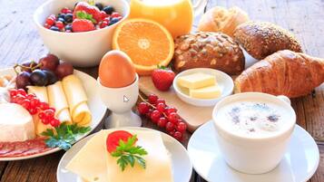 Uma mesa de café da manhã com diversas opções de comida, incluindo frutas, pão, queijo e uma xícara de café.