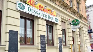 A building with a sign for 'DESSAUER HOF' and 'BECK'S'. There are chalkboards with writing on the windows. - Pension Dessauer Hof (Halle (Saale))