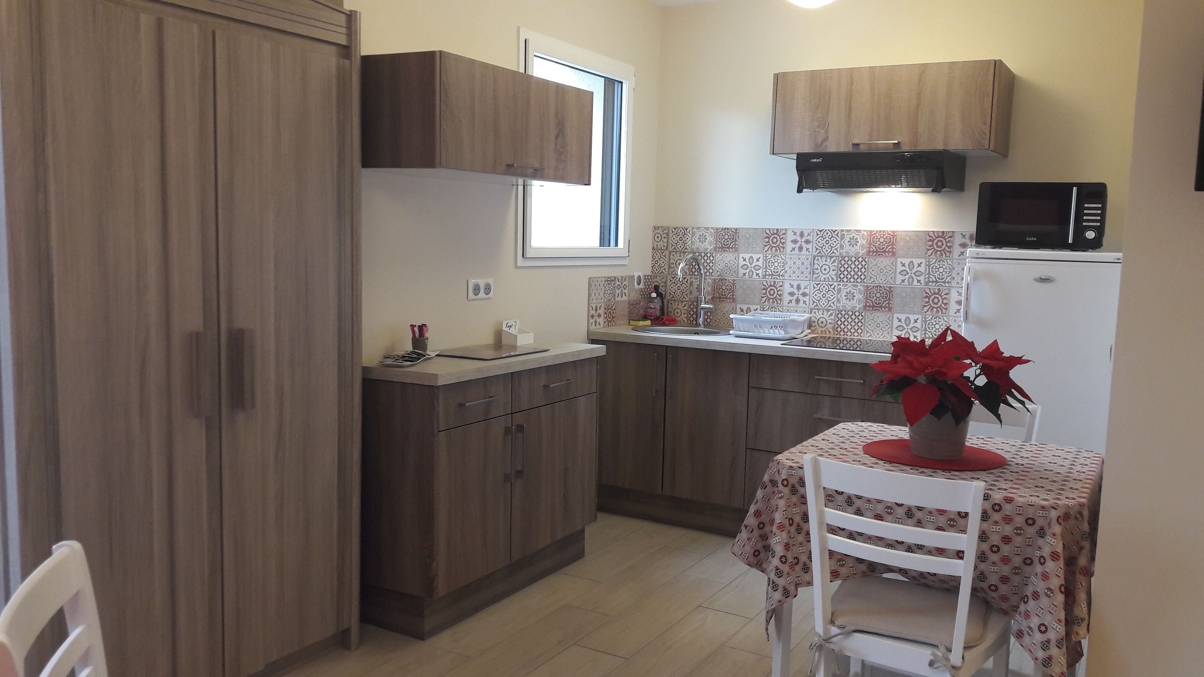 Una cocina compacta con armarios de madera, un microondas y un lavamanos.