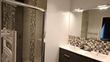 A modern bathroom with a glass shower enclosure, a vanity with a mirror, and a tiled backsplash.