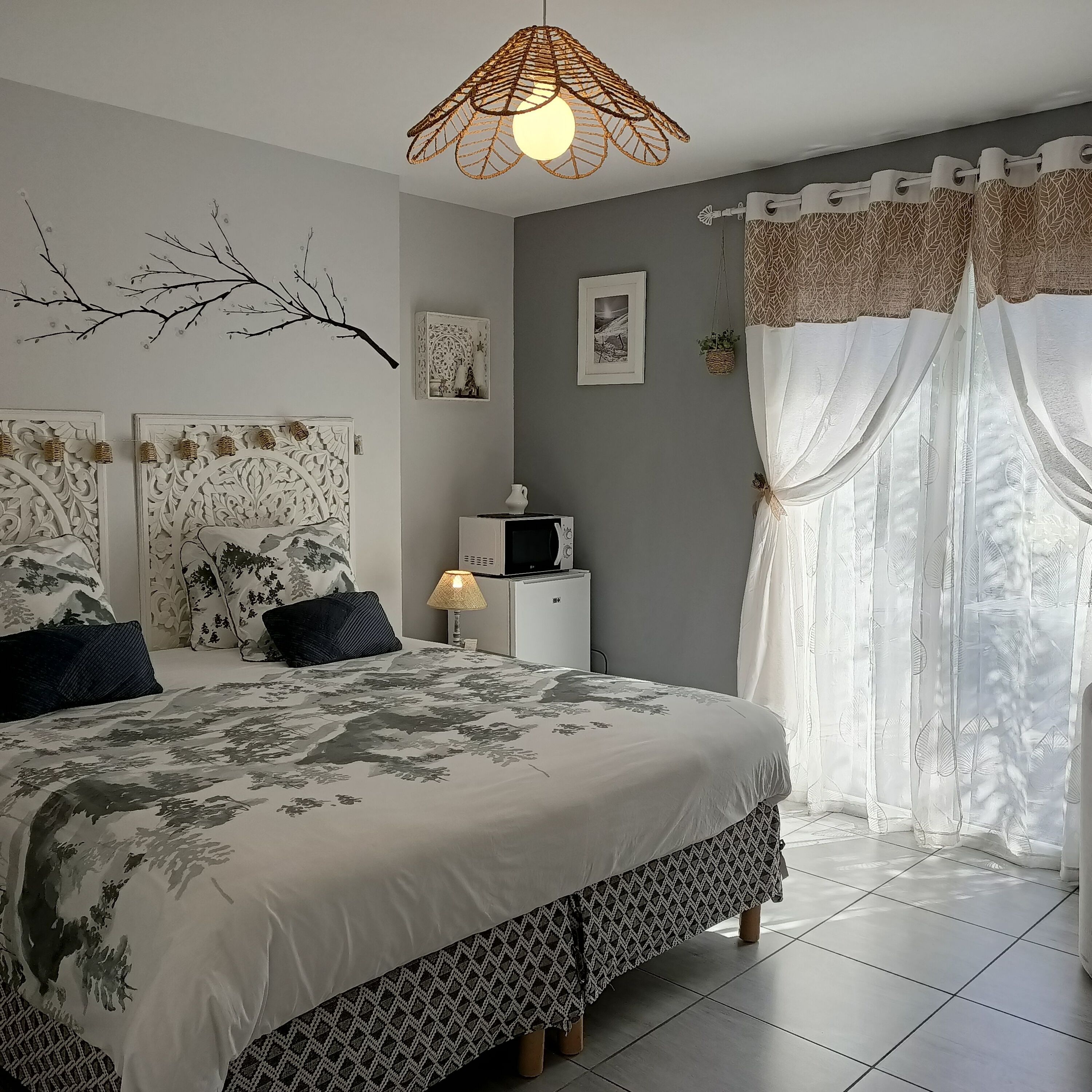 Un dormitorio con cama, lámpara, televisión y decoración en la pared.