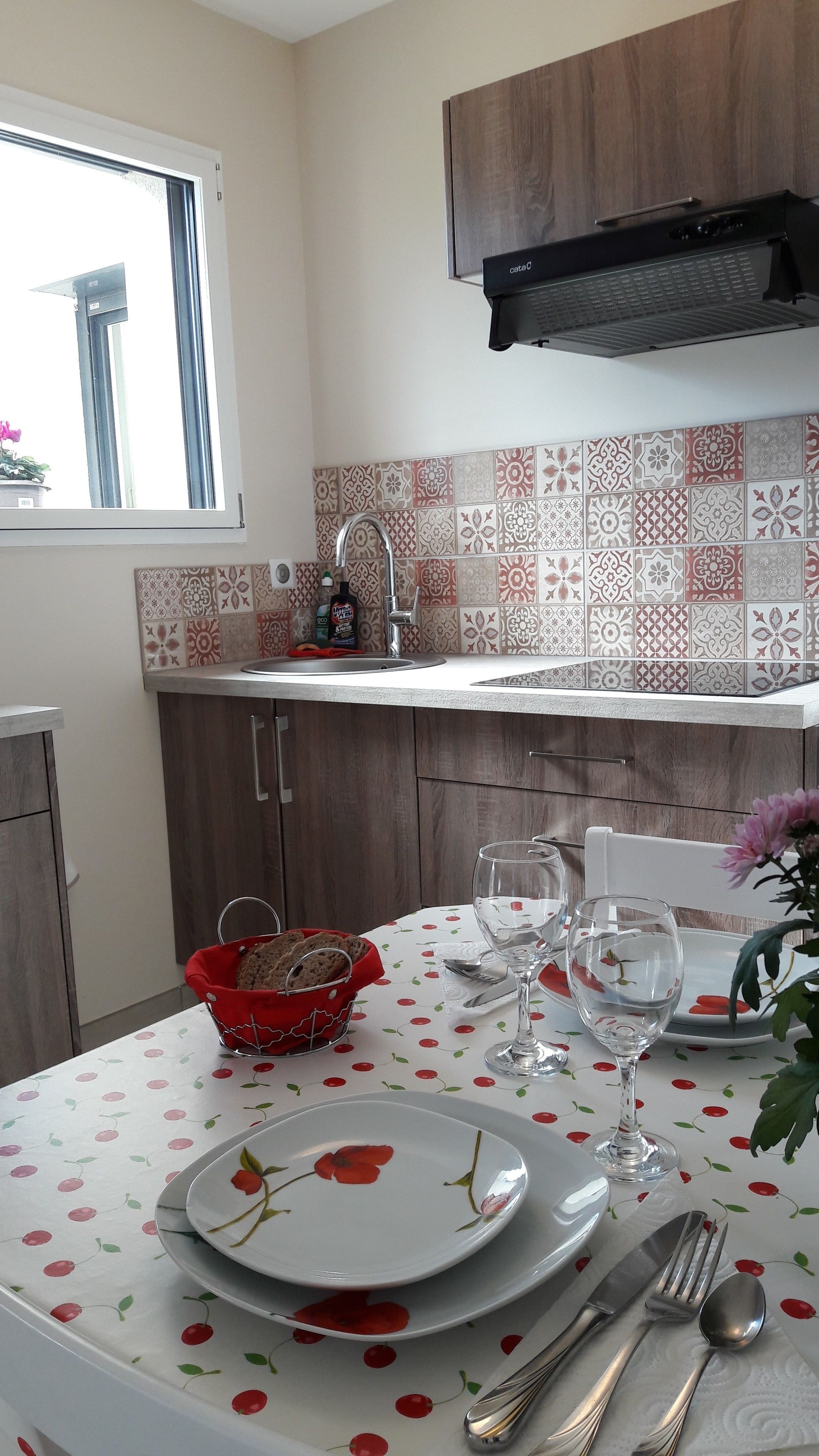 A kitchen with a window, a sink, and a table set for dining with plates, glasses, and cutlery.
