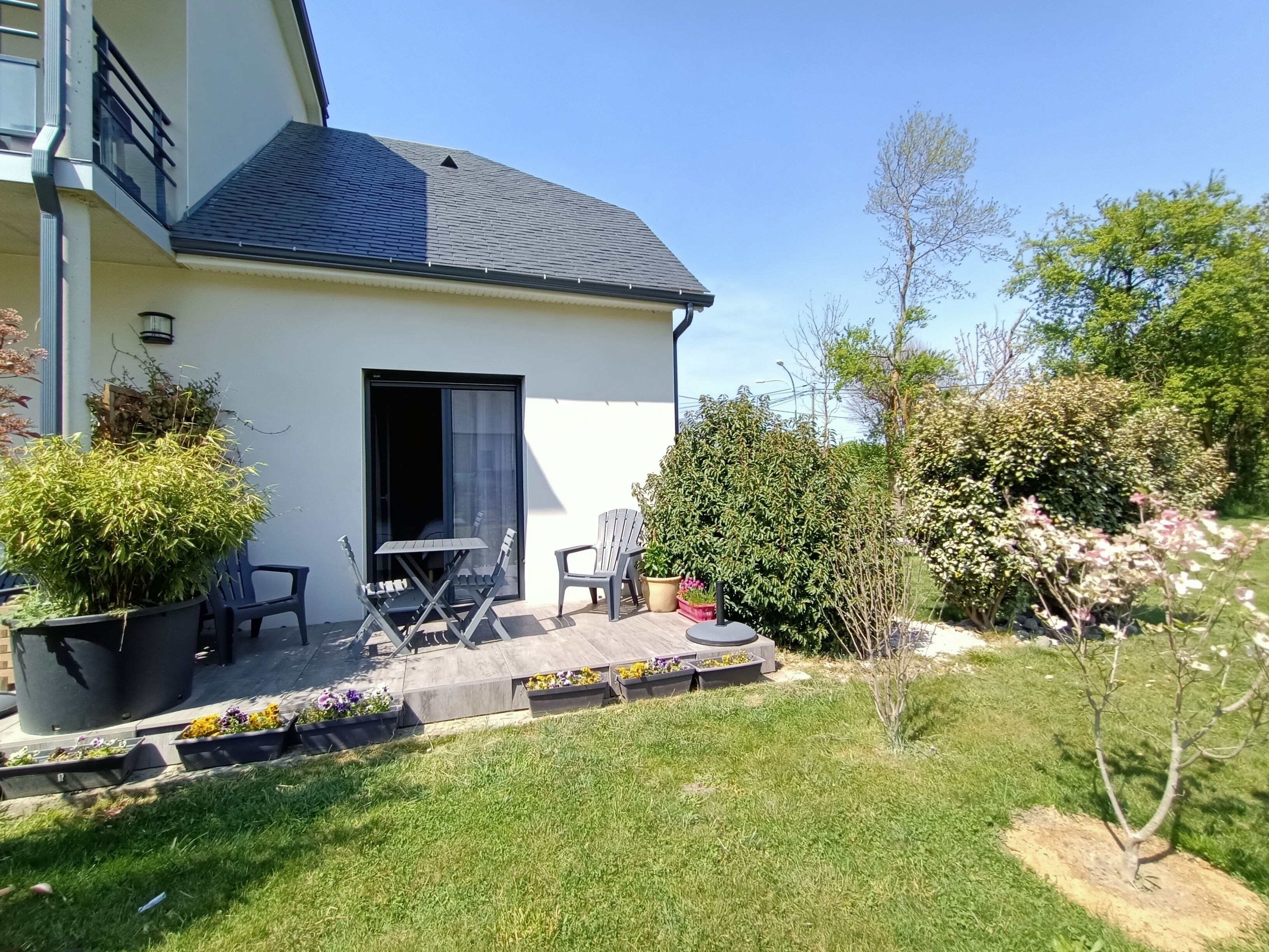 A house with a patio, outdoor furniture, and a garden.