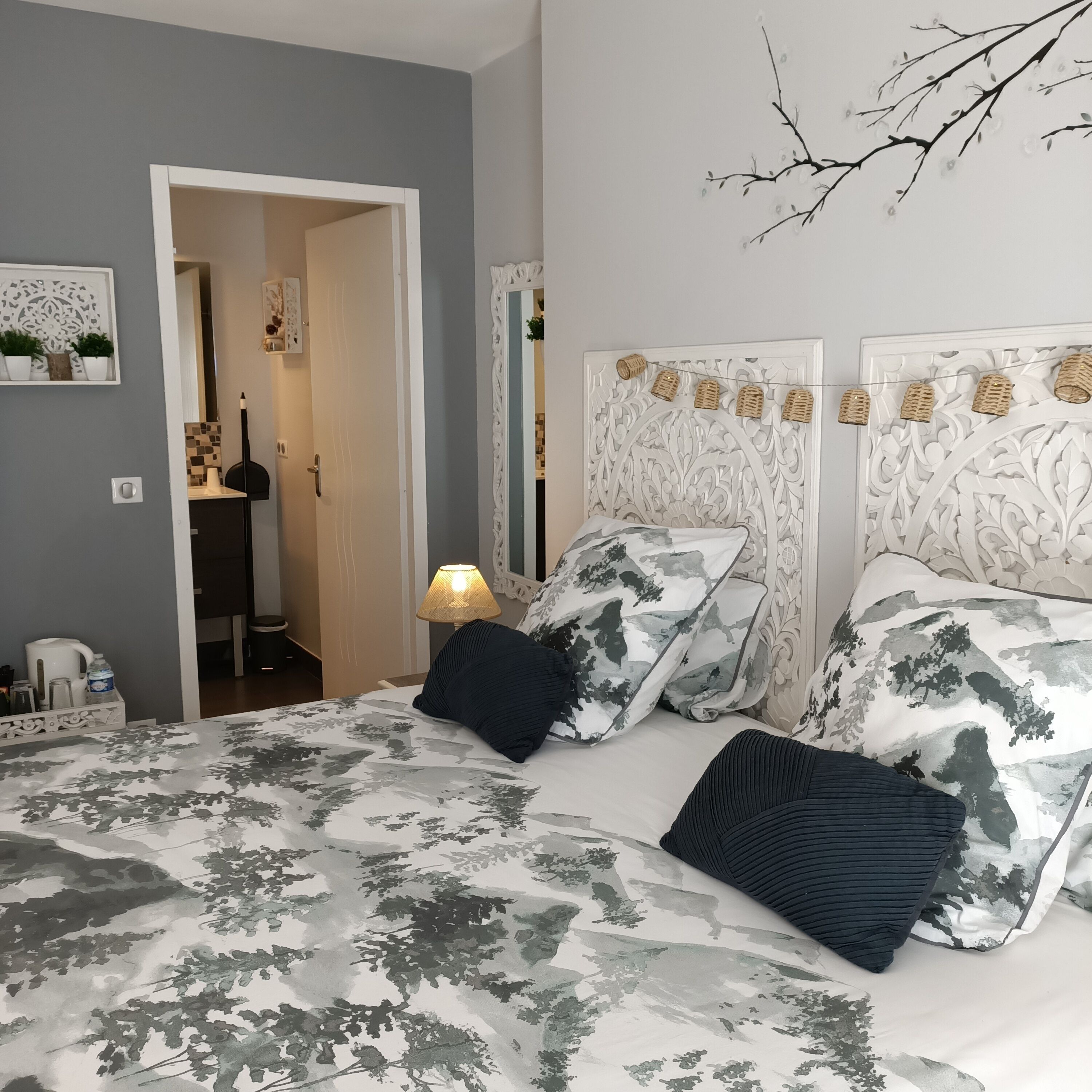 A bedroom with a bed, pillows, a nightstand, a lamp, and a door leading to a bathroom.