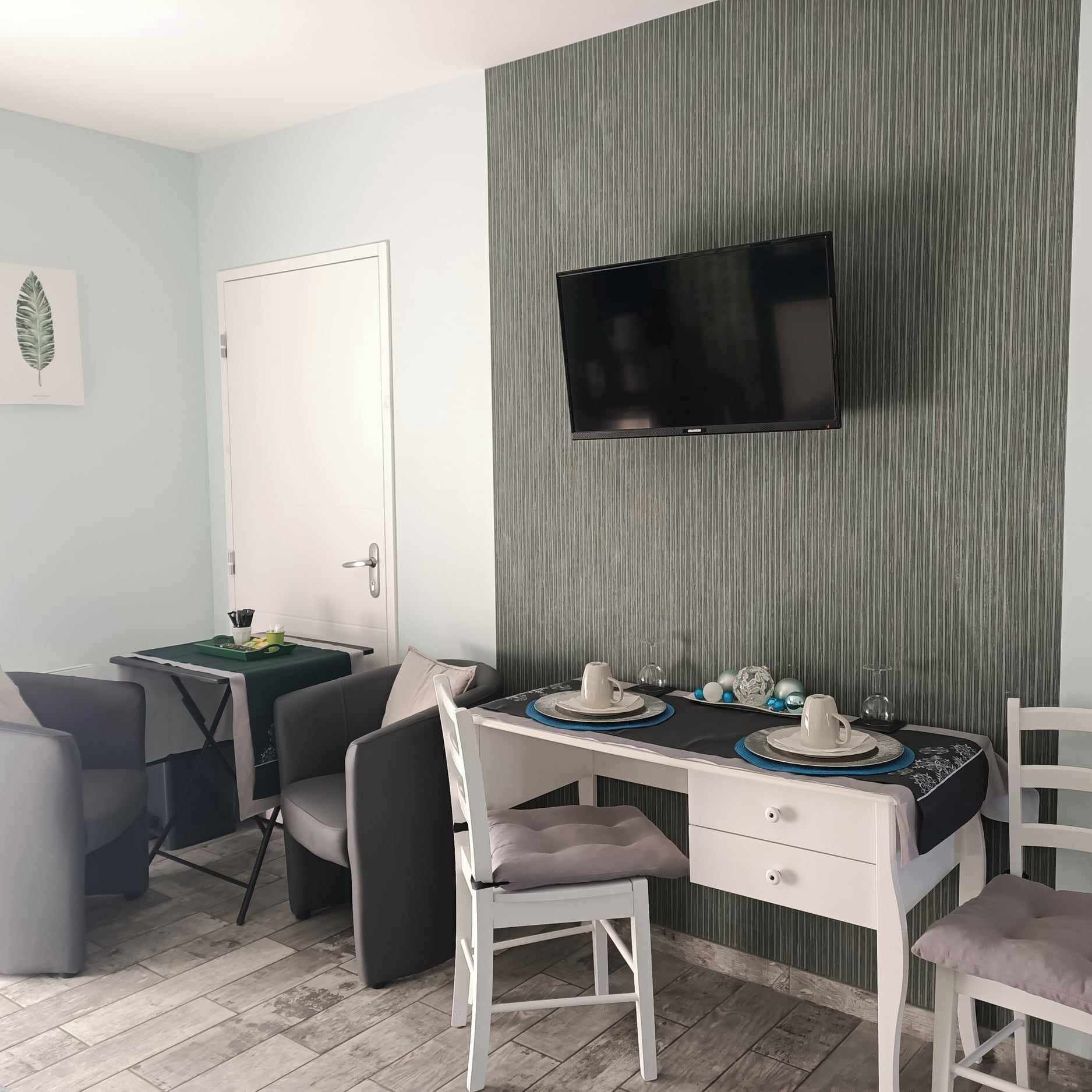 A modern room with a desk, chairs, a television, and a dining area set up.