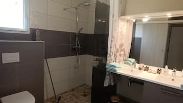 Une salle de bain avec douche, toilettes et lavabo.