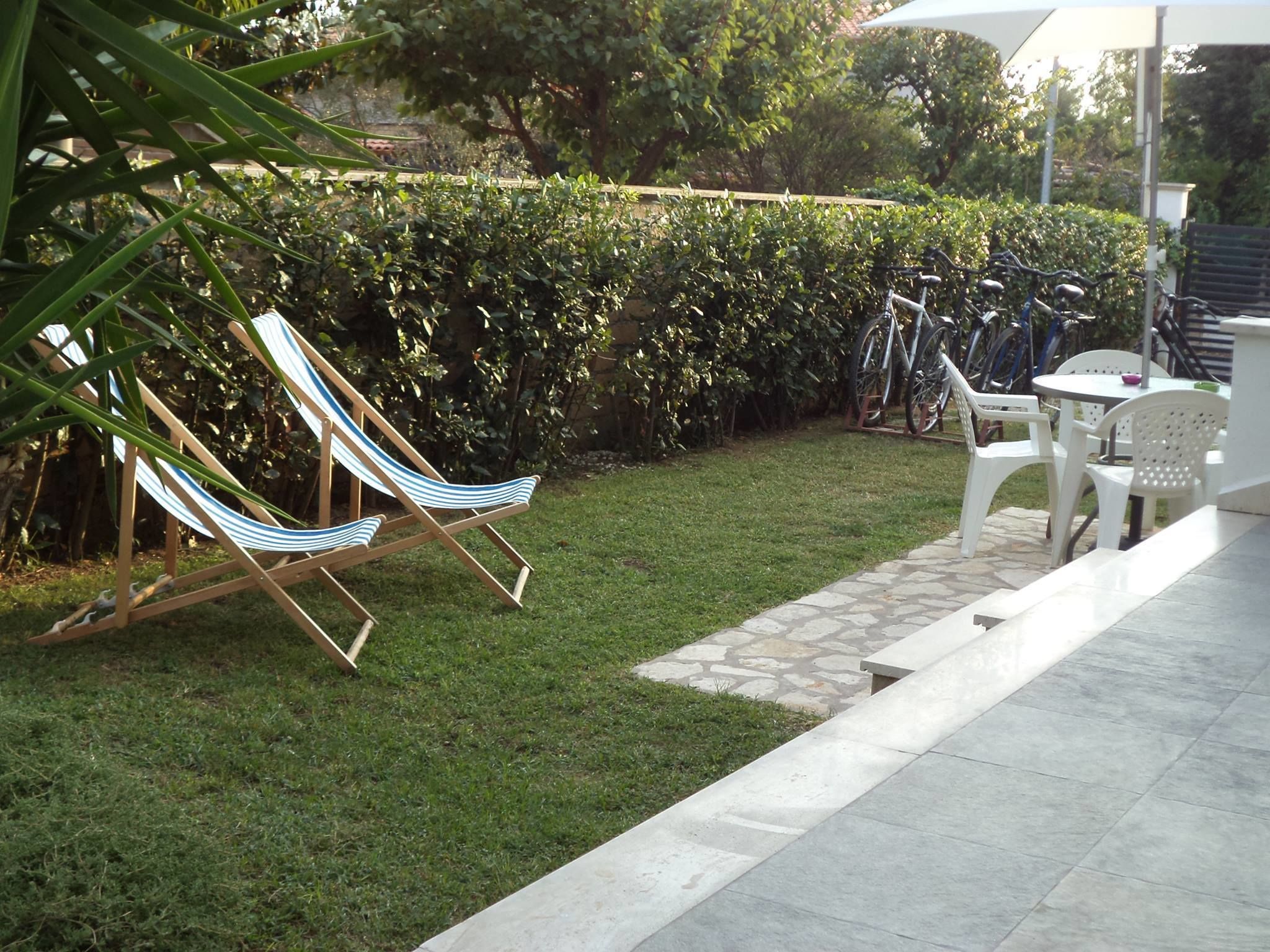 A patio area with a hammock, white plastic chairs, and a bicycle rack.
