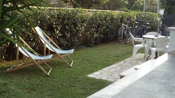 A patio area with a hammock, white plastic chairs, and a bicycle rack.