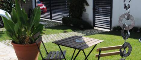 Un patio con una escultura de metal, una planta en maceta y una mesa con sillas.