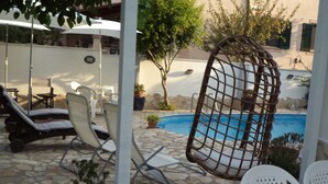 A poolside area with lounge chairs, a hanging chair, and a small pool. - Gens Mundi B&B (Rome)