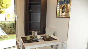 A dining area with a white table, two chairs, and a small shelf with a few items. - Gens Mundi B&B (Rome)