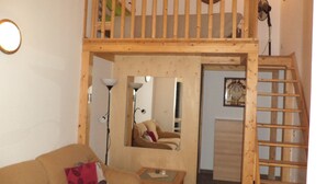 A loft-style room with a wooden staircase, a sofa, a small table, and a mirror. - Gens Mundi B&B (Rome)