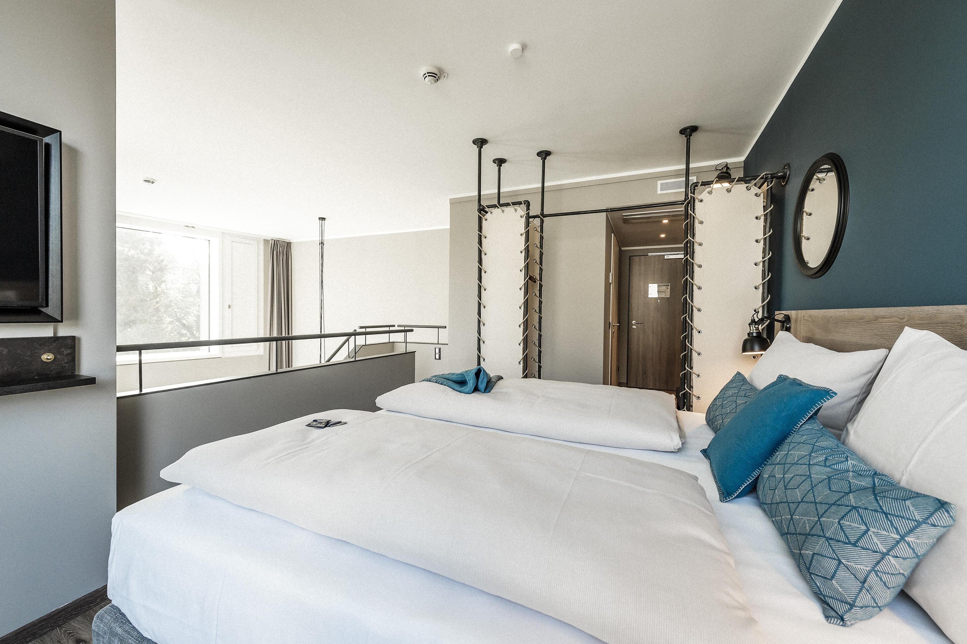 Una habitación de hotel moderna con una cama grande, un televisor y un balcón con barandilla.