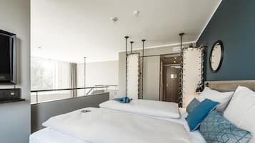 Una habitación de hotel moderna con una cama grande, un televisor y un balcón con barandilla.