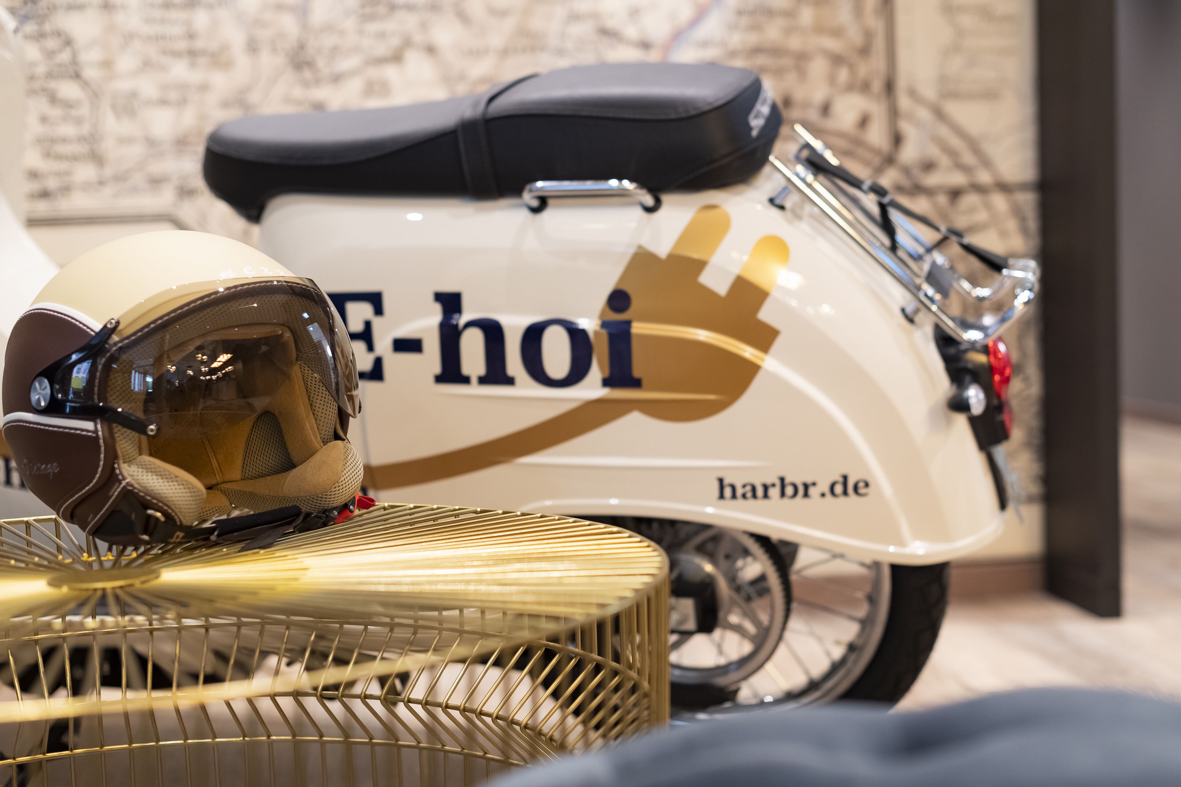 Een witte scooter met een zwart zadel en een logo met de tekst 'E-hoi' en 'harbr.de'.