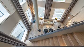 A modern interior with a staircase, large windows, and a seating area with a round table and chairs.