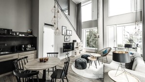 Una cocina moderna con comedor, una sala de estar con sofá y otomanas, y un amplio ventanal con vista a la ciudad.