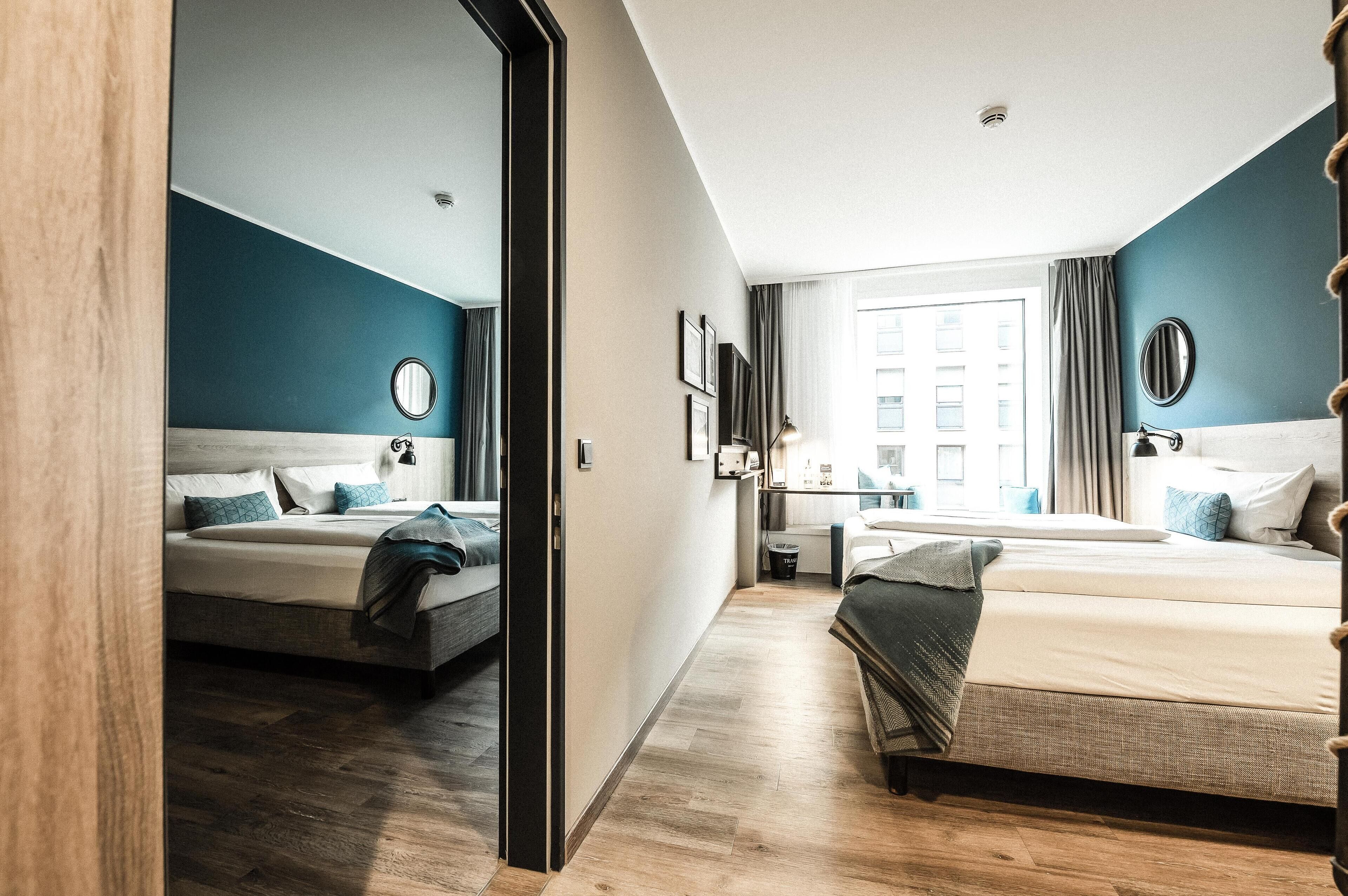 Une chambre d’hôtel moderne avec deux lits, un bureau et une grande fenêtre.