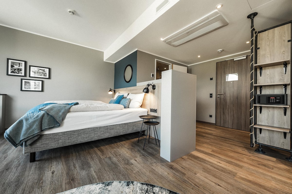 Un dormitorio moderno con cama, mesitas de noche, una lámpara de pared y un armario de madera.