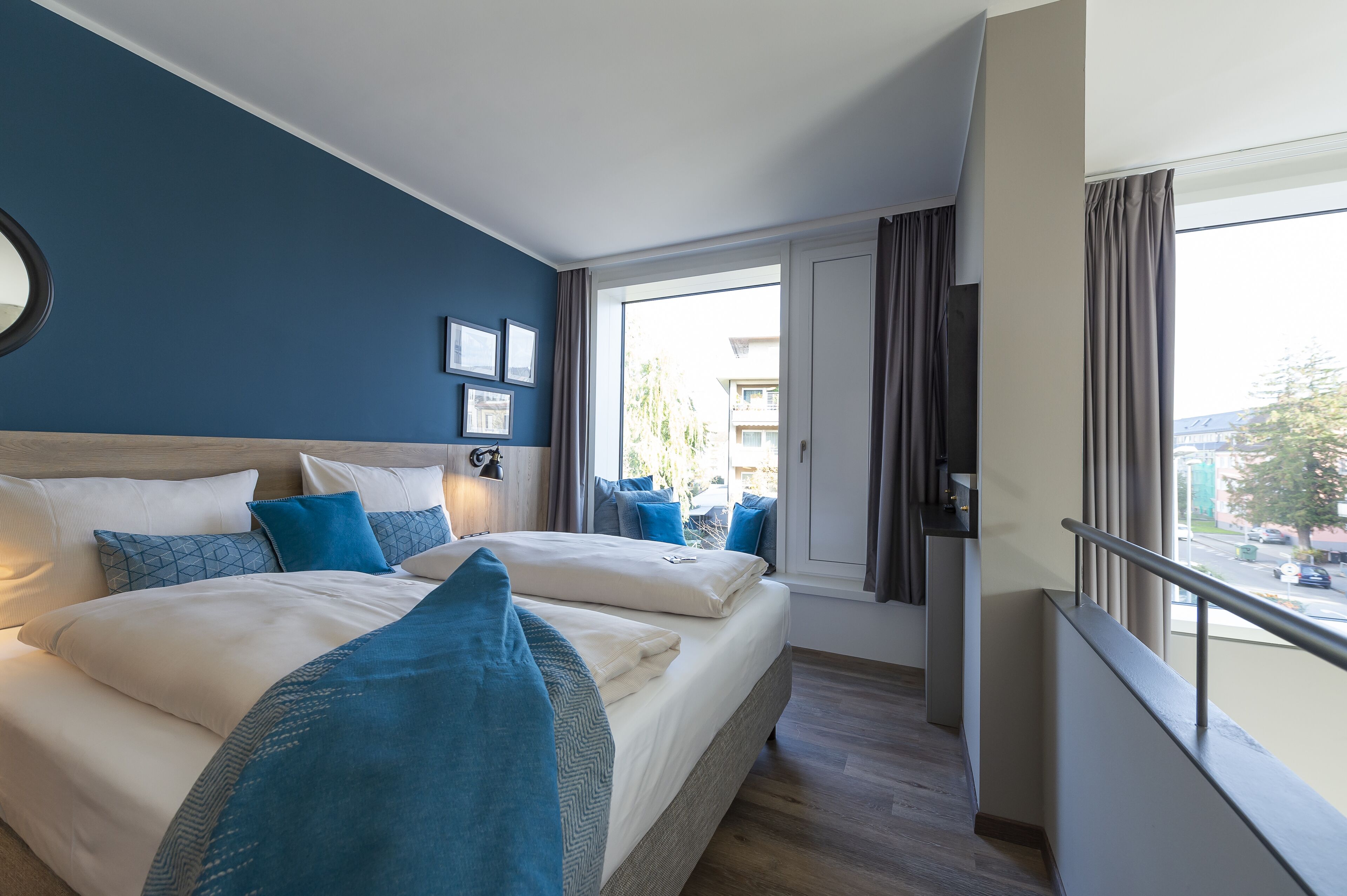 Une chambre d’hôtel avec un grand lit, une vue sur la rue et un balcon doté d’une balustrade.