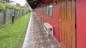 Uma galeria coberta com chão de azulejos, bancos e uma porta com uma placa indicando o quarto número 1.