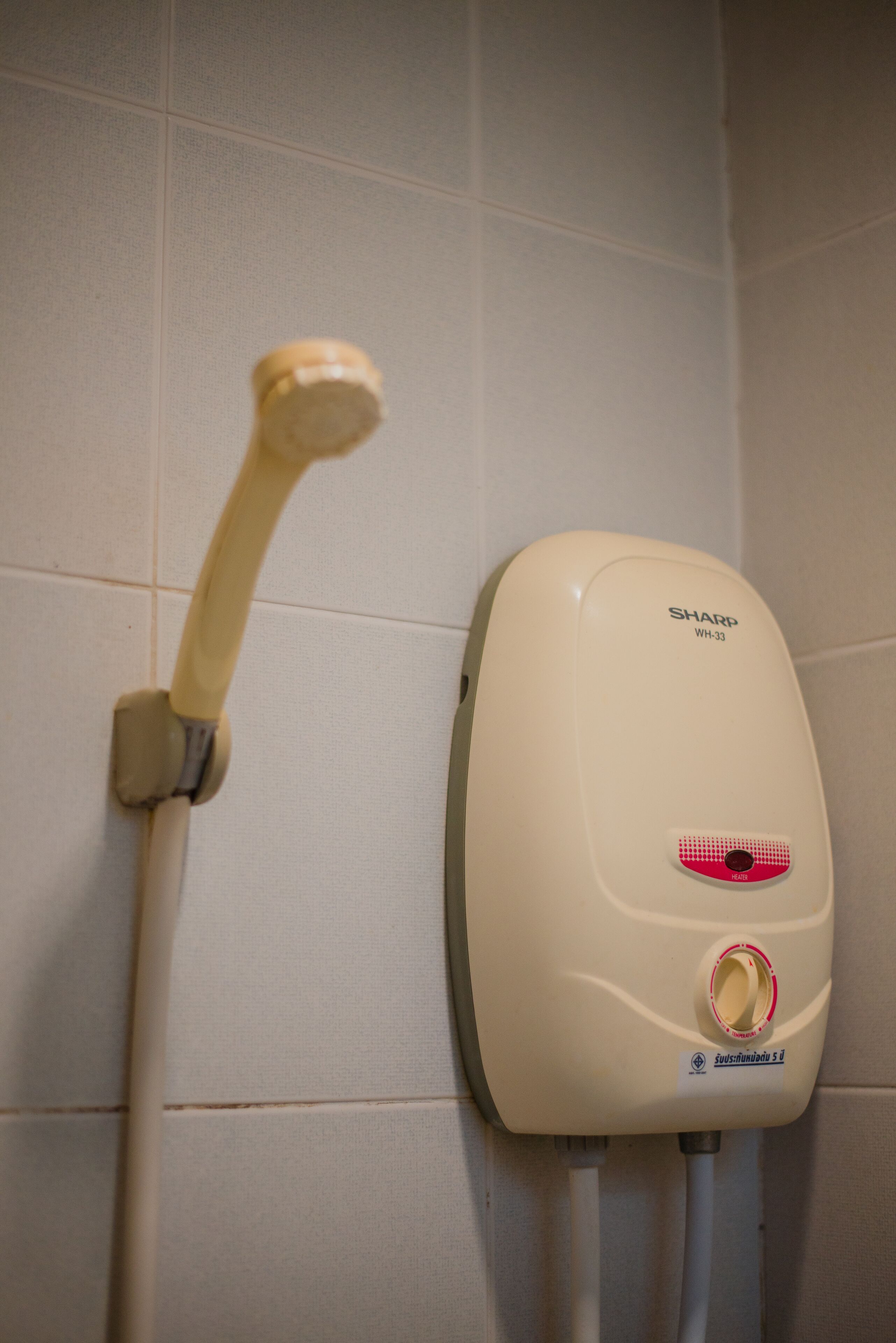 Un pommeau de douche et un panneau de commande fixés sur un mur carrelé.
