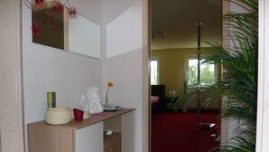 A bathroom with a wooden vanity, a mirror, a red towel, and a potted plant.