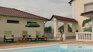 A swimming pool with lounge chairs and an umbrella.
