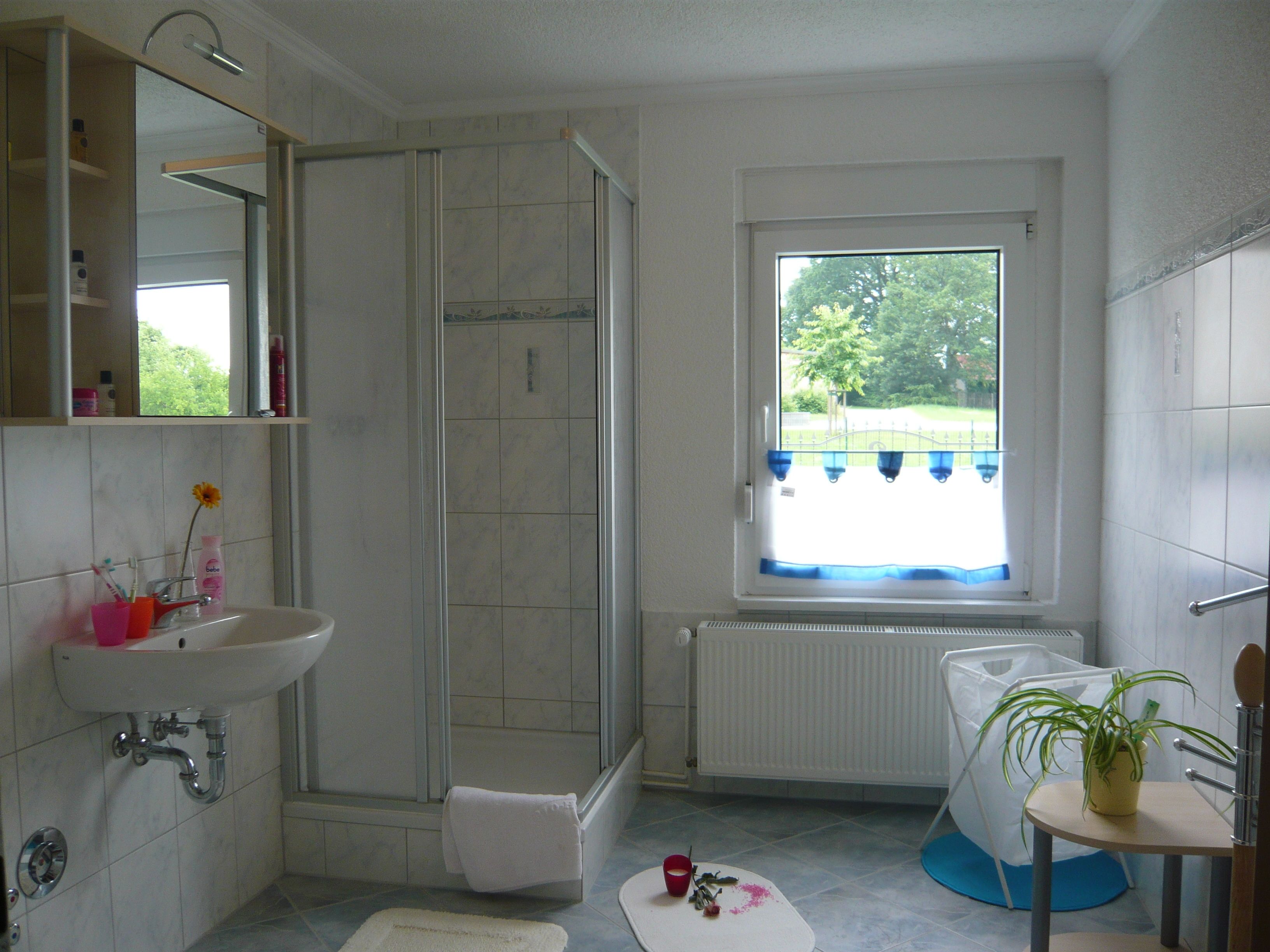 Un baño con ducha, lavamanos y ventana.