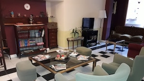 A living room with a checkered floor, a coffee table with magazines, a television, a bookshelf, and a sofa.