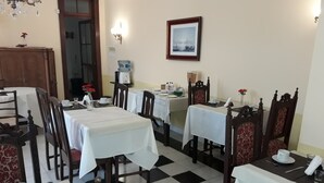 A dining area with multiple tables and chairs, a chandelier, and a framed picture on the wall.