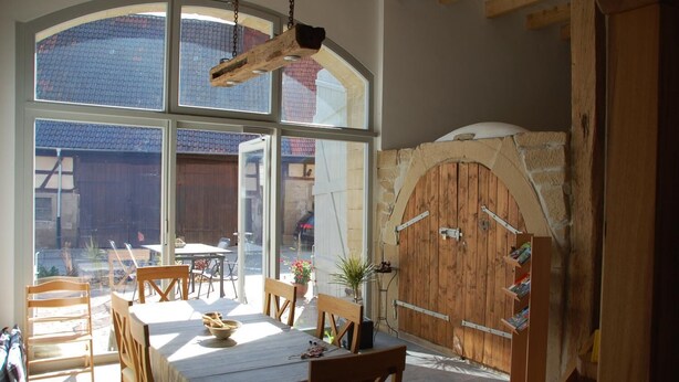 Un coin repas avec une table et des chaises, une porte en bois et une grande fenêtre.