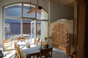 Un comedor con una mesa, sillas, una puerta de madera y un ventanal grande.
