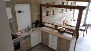 Une cuisine compacte équipée d’un évier, d’un lave-vaisselle et d’un plan de travail en bois.