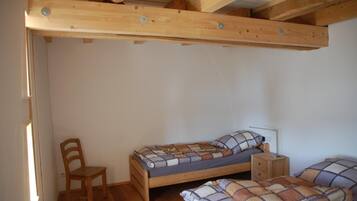 A small, single-bedroom room with a wooden bed, a chair, and a nightstand.