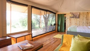 Ein Zimmer mit einem Bett, einem Holztisch, einer Bank und einem großen Fenster.