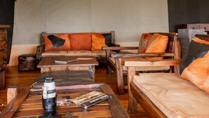 Eine Zelteinrichtung mit mehreren Sitzbereichen, darunter Sofas und Bänke, sowie ein Tisch mit Kamera und Buch.