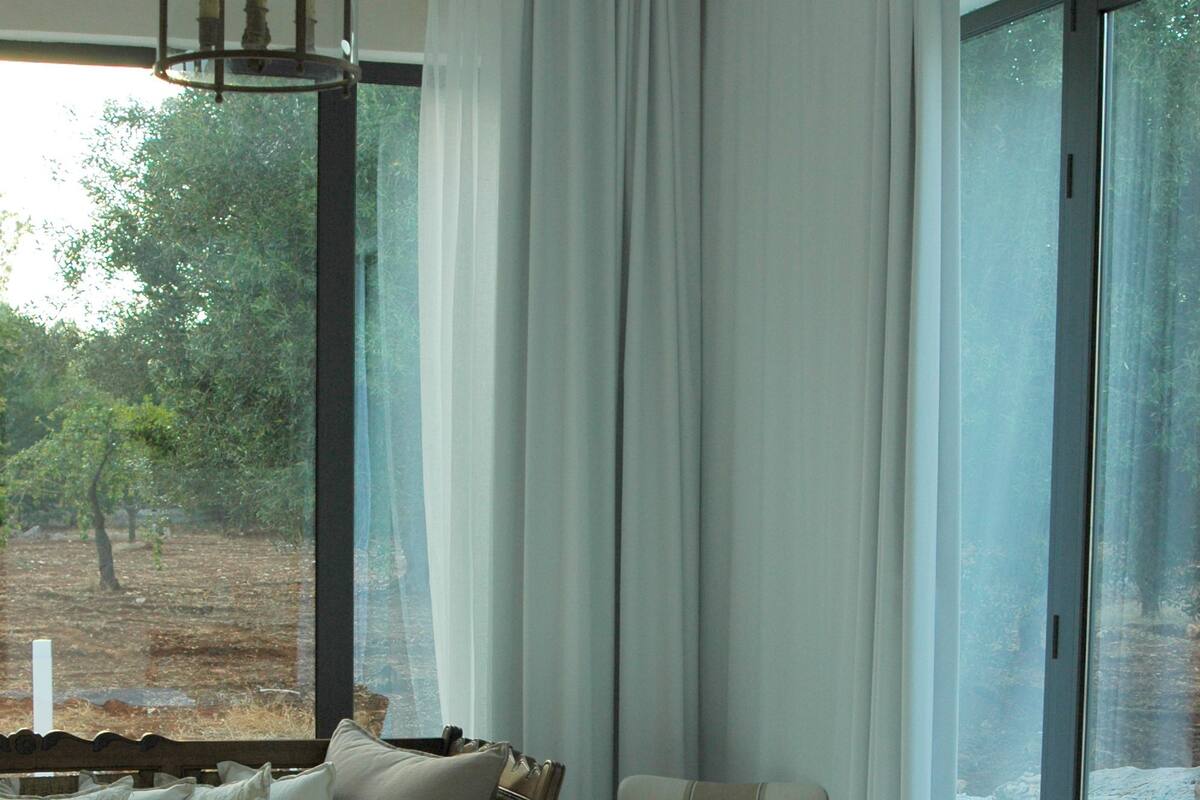 A bedroom with a large bed, a chair, and a view of the outdoors through a window.