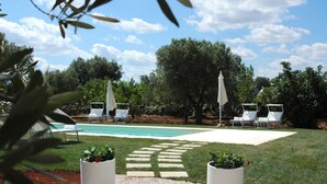 A pool area with lounge chairs and umbrellas, surrounded by trees and a clear sky. - Ulivi Al Sole - Charming B&B (Francavilla Fontana)