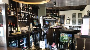 Un espace bar doté de plusieurs tireuses à bière, d’une caisse enregistreuse et d’un tableau affichant le menu.
