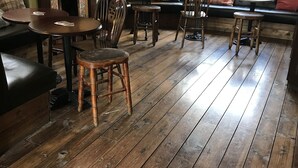 Une pièce chaleureuse avec une cheminée, un plancher en bois, un canapé et une table à manger avec des chaises.