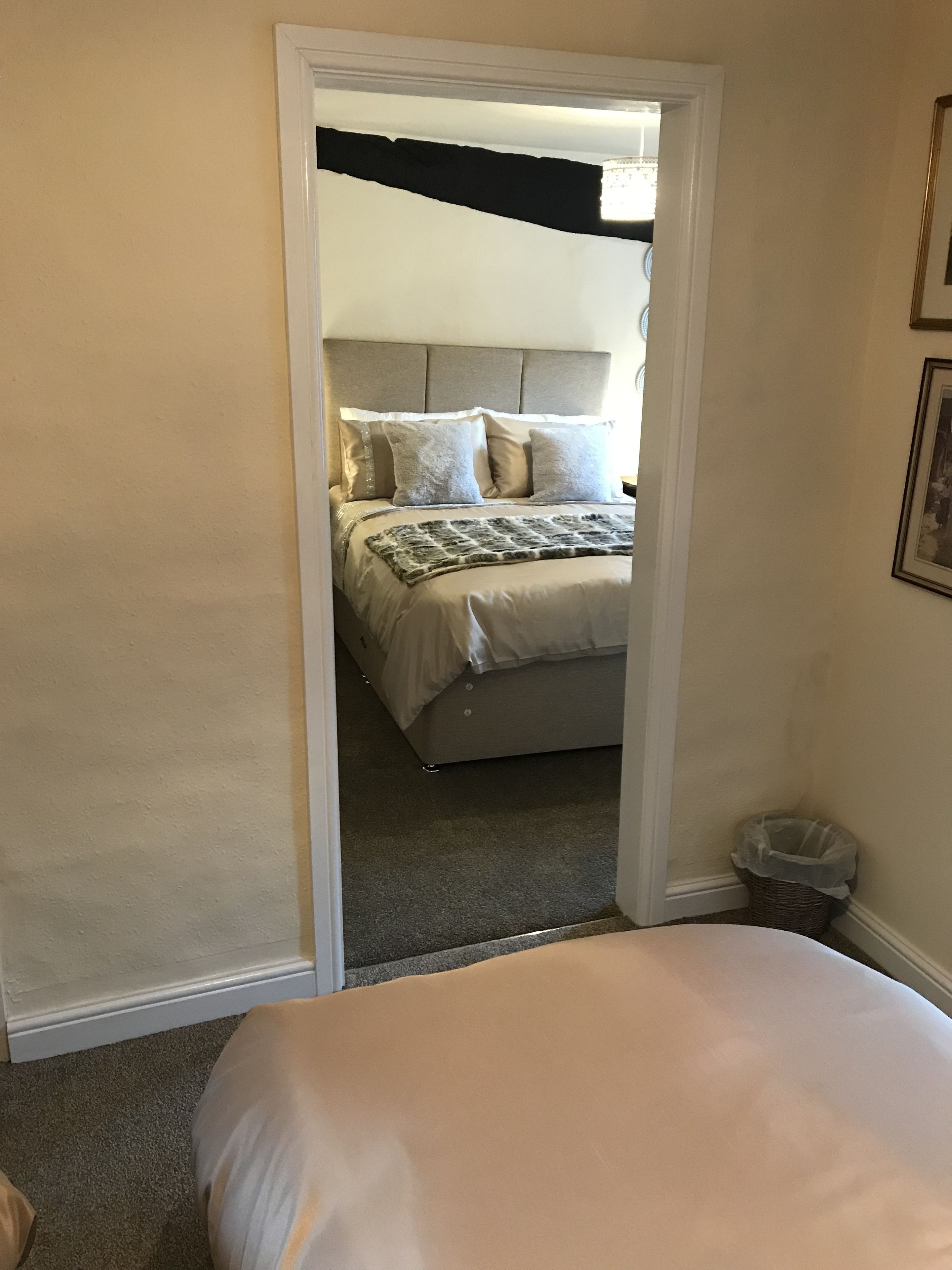 Une chambre à coucher avec un lit, une tête de lit, un tableau accroché au mur et une poubelle.