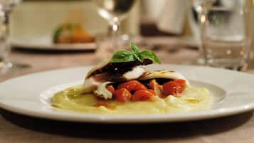 A plate of food with a piece of meat, vegetables, and a garnish on a white plate.