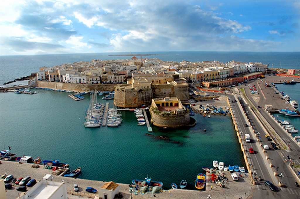 A coastal town with a fortified castle, marina, and a road leading to the harbor.