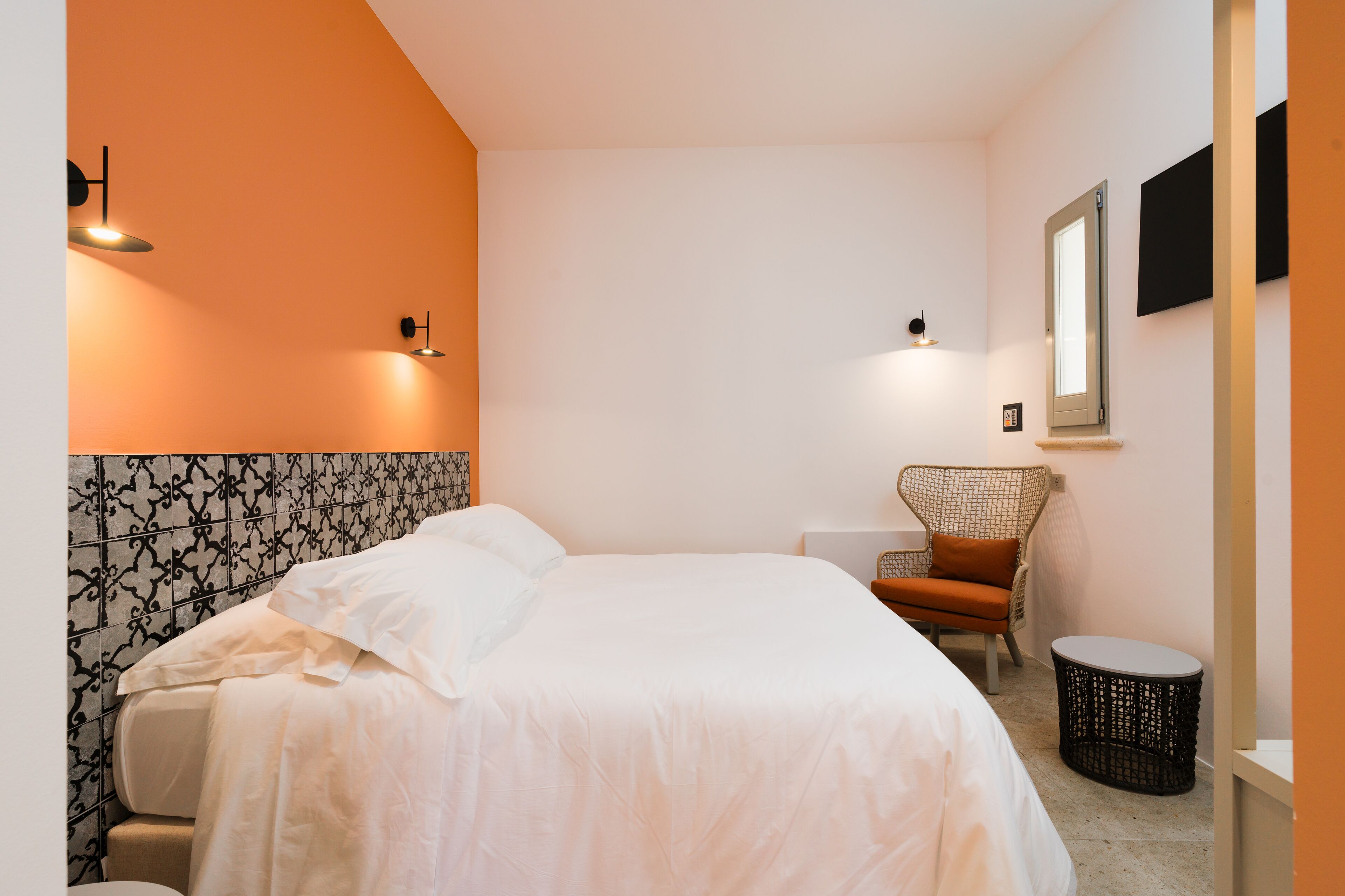 Ein Hotelzimmer mit Bett, Sessel, rundem Tisch und Wandleuchten.
