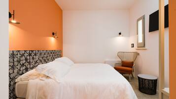 Ein Hotelzimmer mit Bett, Sessel, rundem Tisch und Wandleuchten.