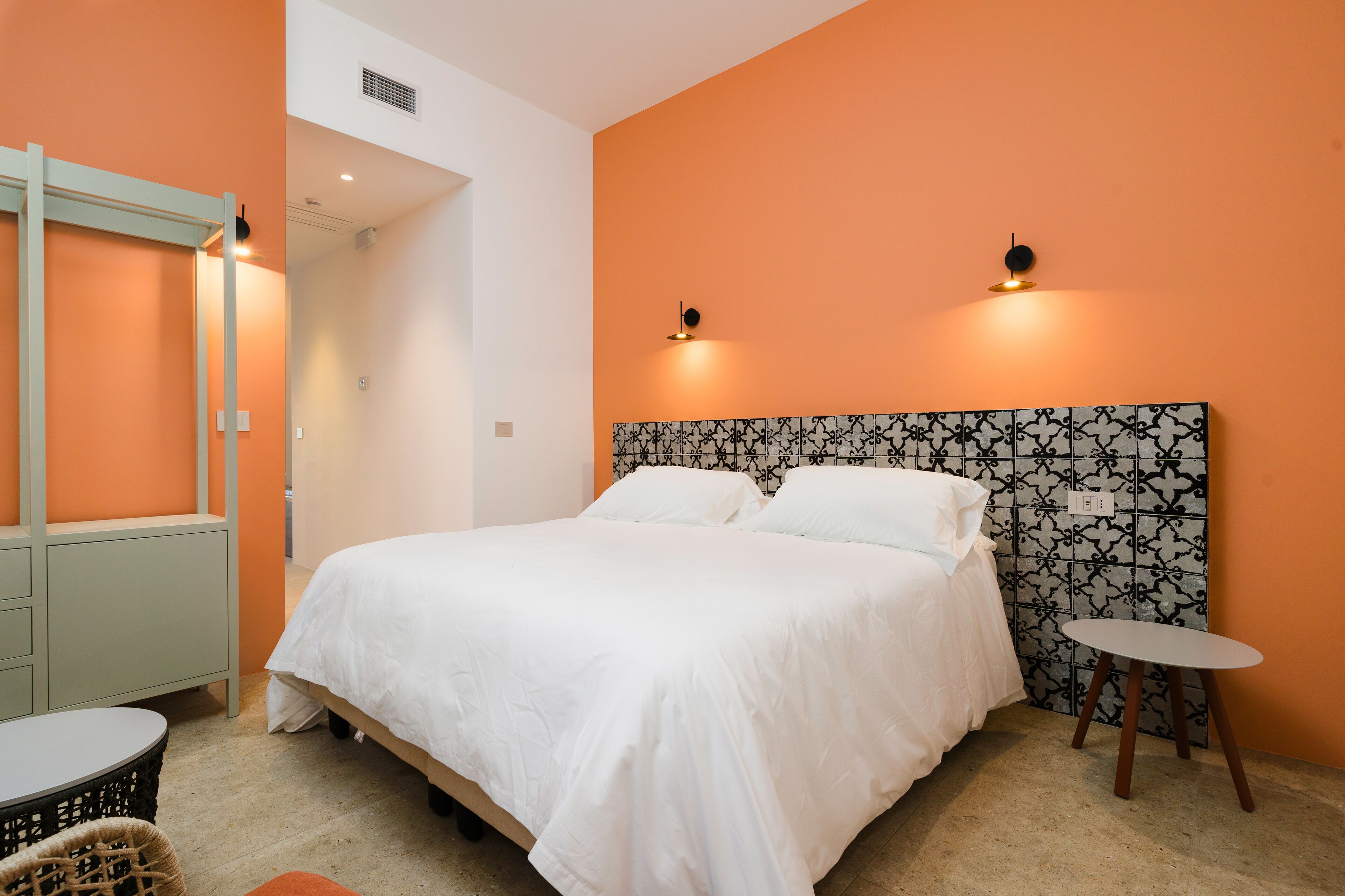 A neatly arranged bedroom with a bed, a small table, a chair, and a mirror.