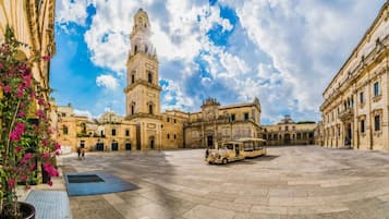 Un amplio patio con una imponente torre del reloj, rodeado de edificios históricos.